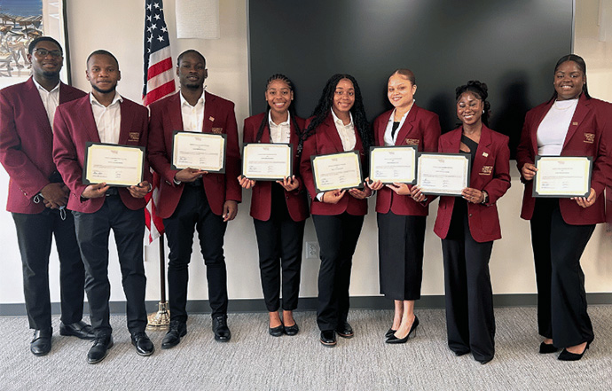 UDC Students standing in a row wearing burgundy jackets and holding certificates