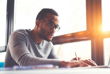 Male college student sitting at a desk and working on a laptop