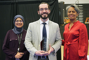 Three UDC faculty members. The man in the middle holds an award.