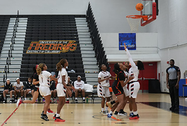 UDC women's basketball team playing a game in a gym.