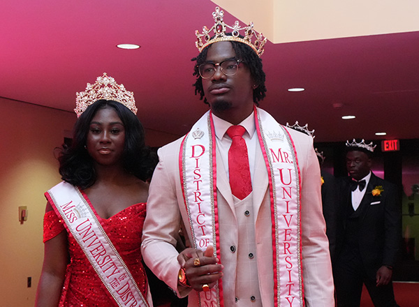 The previous Mr. and Misses UDC walking into the theater wearing royal attire.