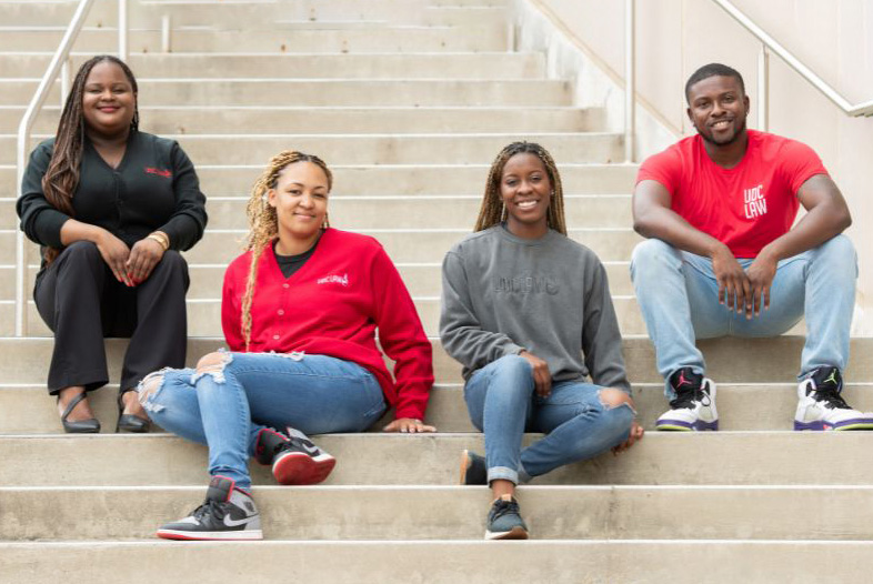 two female and two male UDC law students stilling on steps