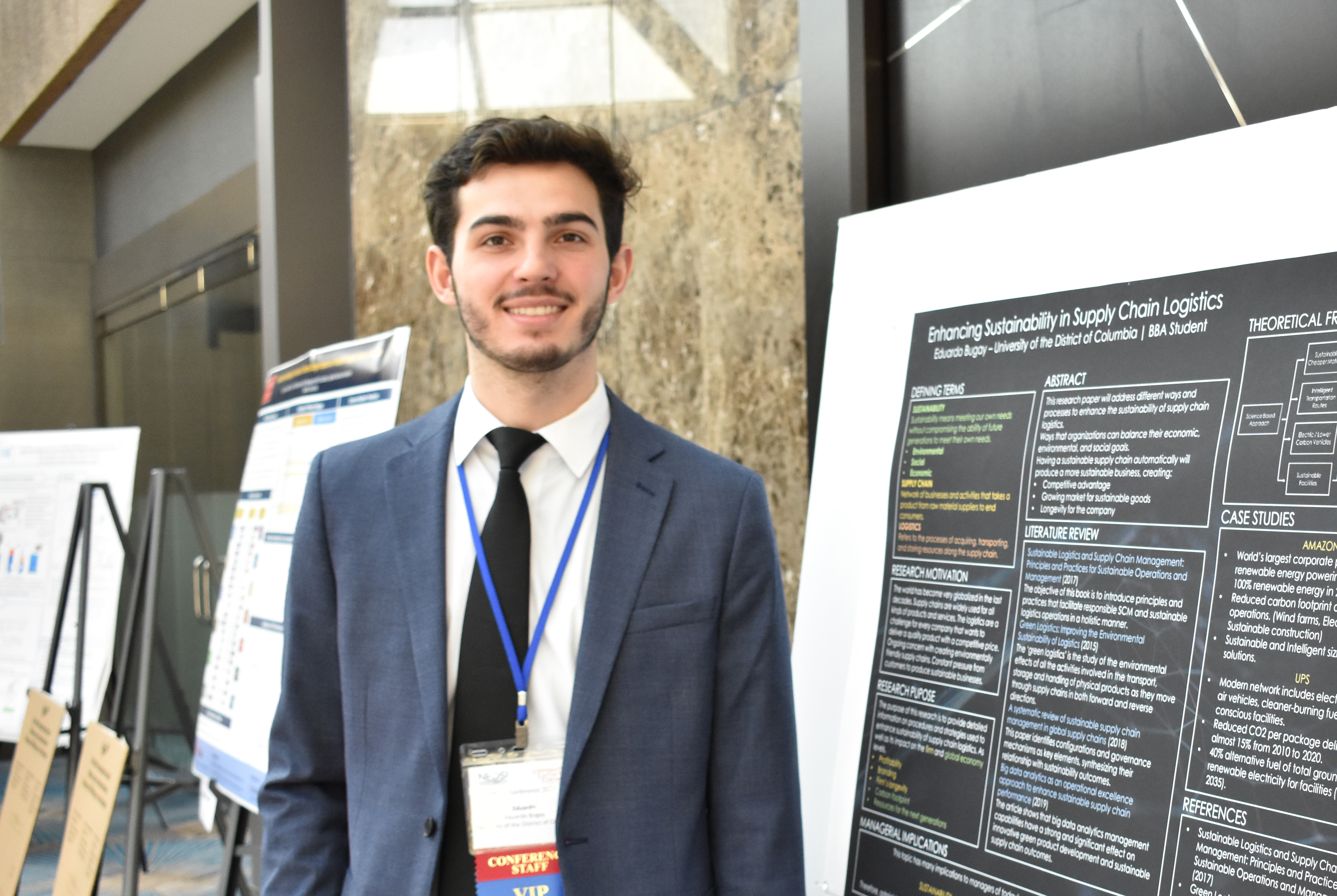 Male business student in a suit standing in front of a presentation board