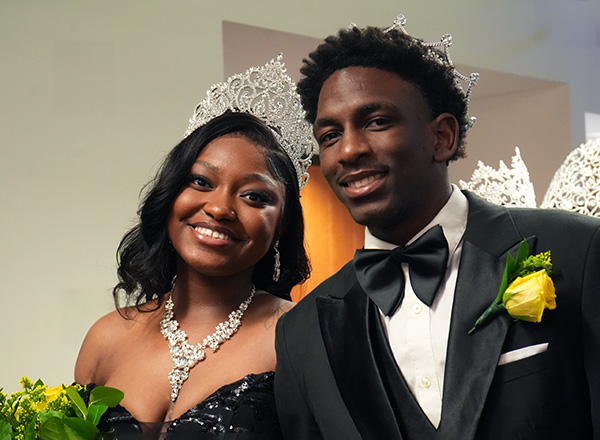 A man and woman in formal attire looking at the camera and smiling