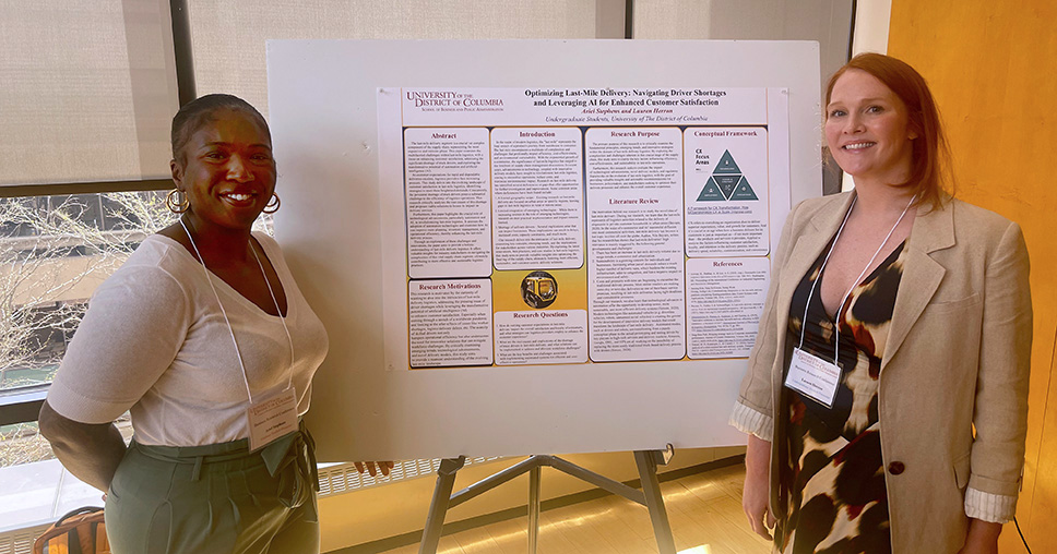 Two SBPA students in front of their posters at Research Week 2024