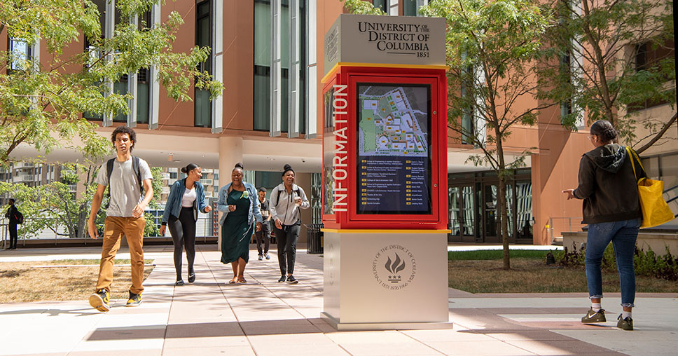 UDC students on the Van Ness campus near an information tower